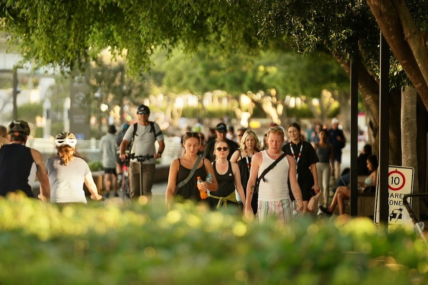 Crowds of people walking at Brisbane's South Bank on a sunny afternoon.