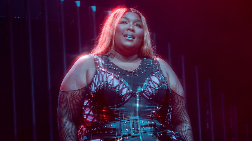 Lizzo stands on stage at Splendour In The Grass in a black leather outfit.