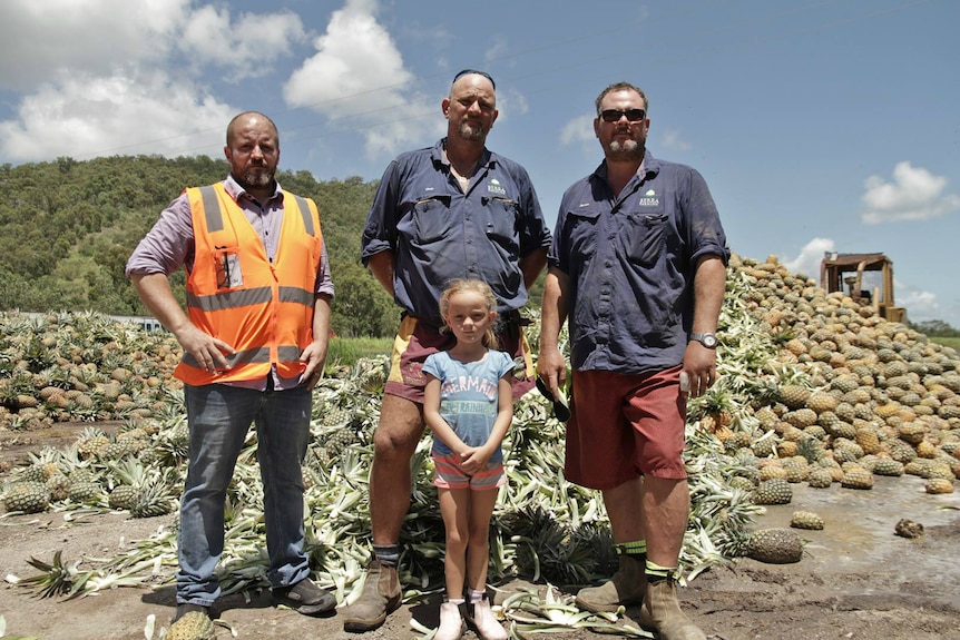 The farmers standing by a pile of rotting fruit.