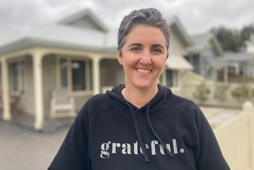 A woman stands in front of a house.