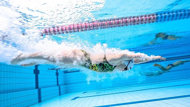 A swimmer underwater in a pool.