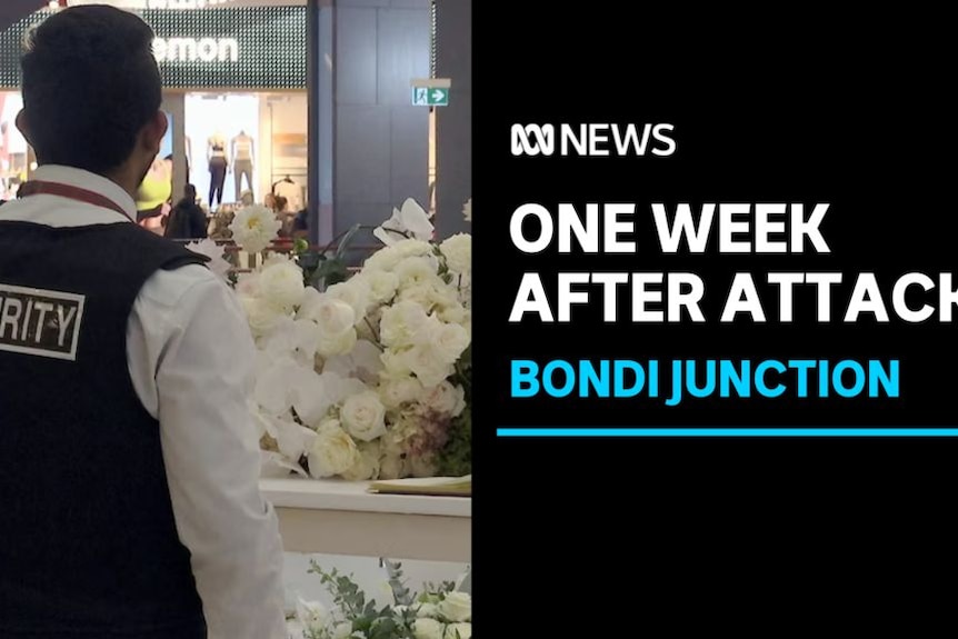 One Week After Attack, Bondi Junction: A security guard at a floral tribute in a shopping centre.