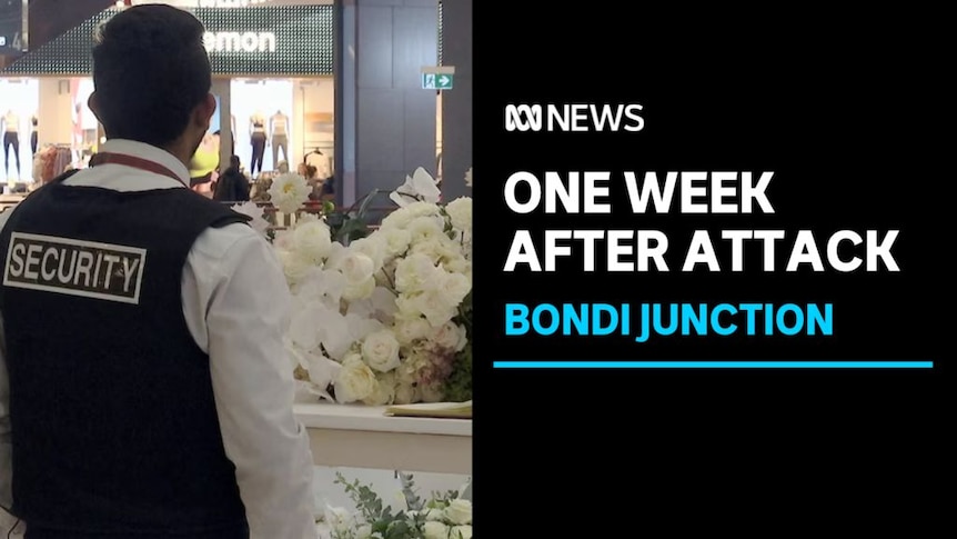 One Week After Attack, Bondi Junction: A security guard at a floral tribute in a shopping centre.