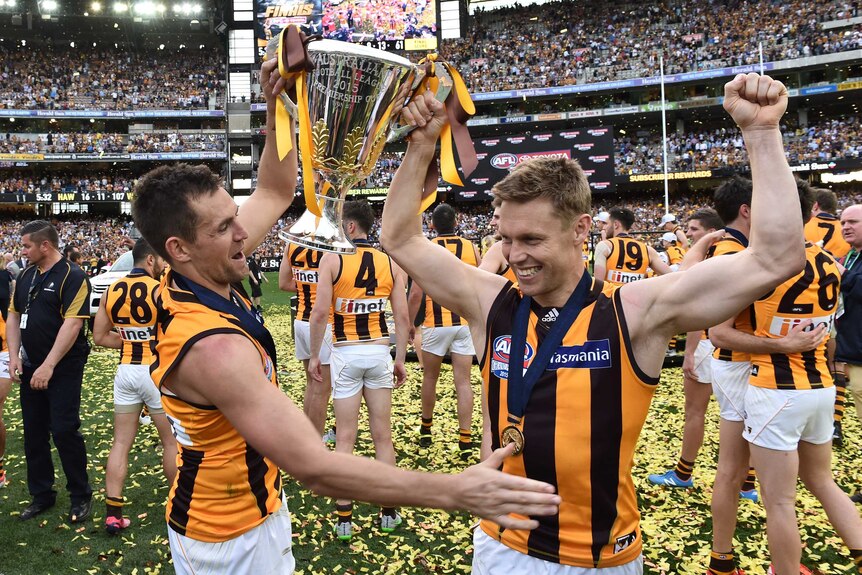 Hawthorn captain Luke Hodge and midfielder Sam Mitchell celebrate on the MCG with the 2015 AFL premiership cup held aloft.