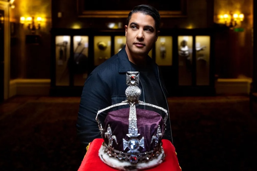 Marc Fennell stands next to the British Crown Jewels.