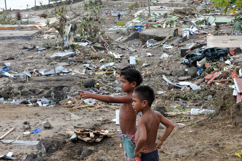 Boys survey the ruins of Salebata village on the south coast of Samoa on September 30, 2009