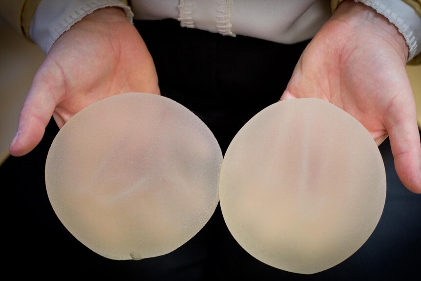 A breast surgeon holds two silicon implants at a clinic in Sydney.
