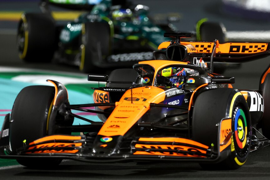 Oscar Piastri en su McLaren naranja, doblando una curva durante una carrera nocturna.