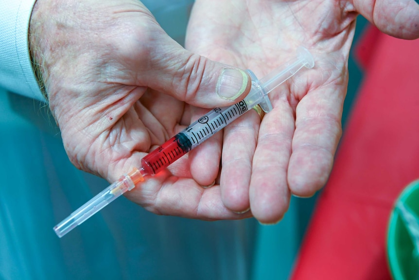 A doctor holding a needle.