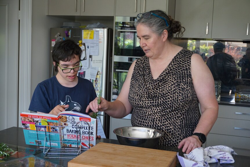 A woman and a child following a baking recipe from a cook book.