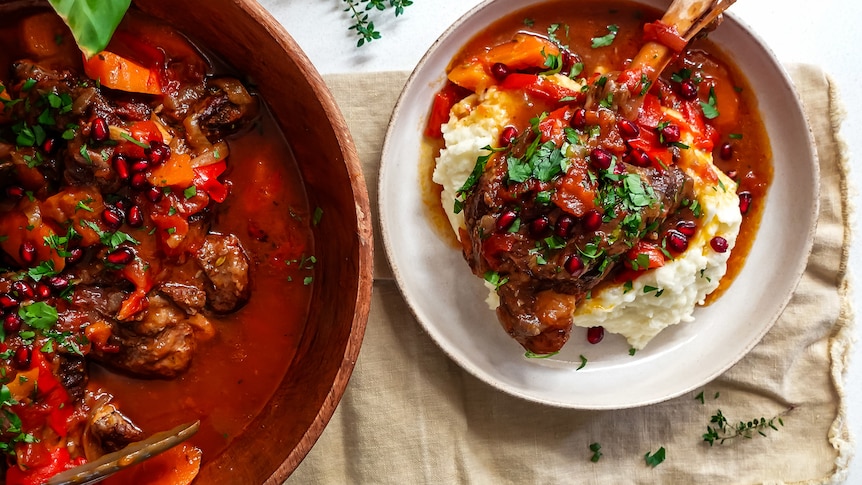 Slow-cooked lamb shanks with pomegranate sauce in a pot, and also in a bowl served atop a heaping of mashed potato.