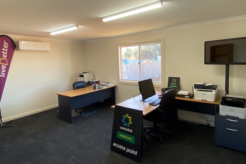 An office with a computer and signs for centrelink and live better.