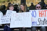 A protester holds a sign that reads: "Paedophiles in jail not the senate".