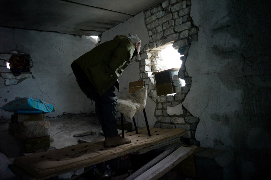 A Ukrainian marine observes separatist positions through artillery damage at his frontline outpost, a former sanatorium.