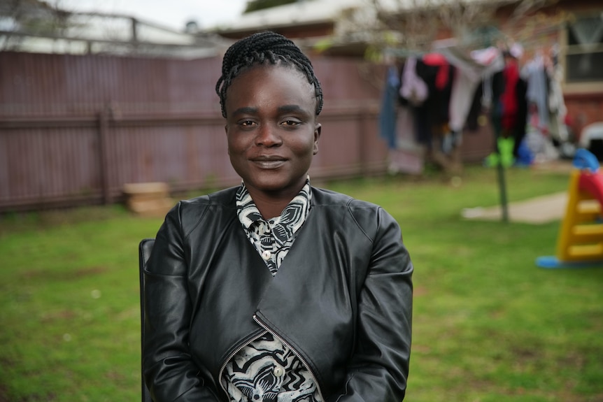 A woman sitting on a chair in her backyard.