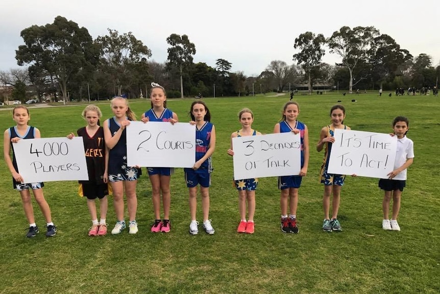 Young netballers hold up a sign calling for more facilities in the Stonnington area.