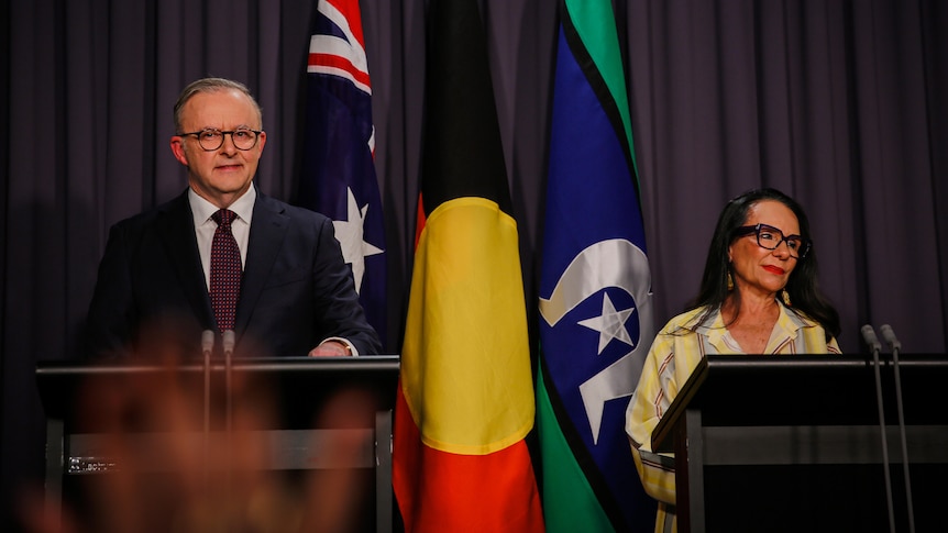 Albanese and Burney stand behind podiums in front of the Australian, Indigenous and Torres Strait flags