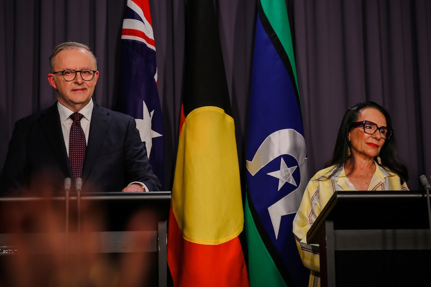 Albanese and Burney stand behind podiums in front of the Australian, Indigenous and Torres Strait flags