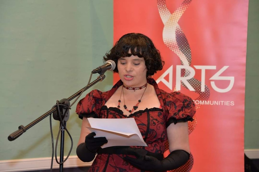 a lady reads at a podium