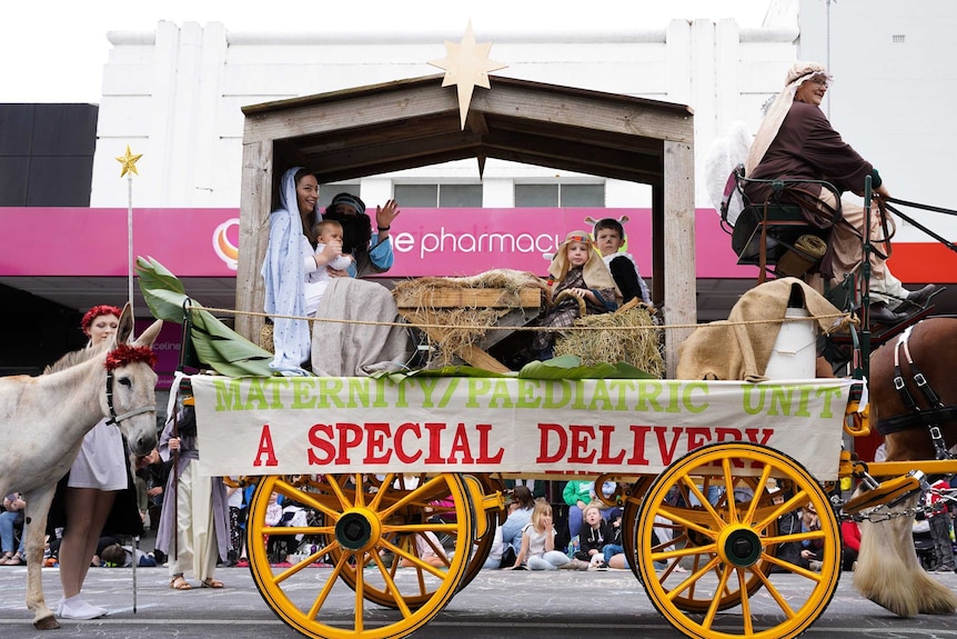 A nativity scene takes place on a cart pulled by horses- sign reads "maternity/paediatric unit a special delivery".