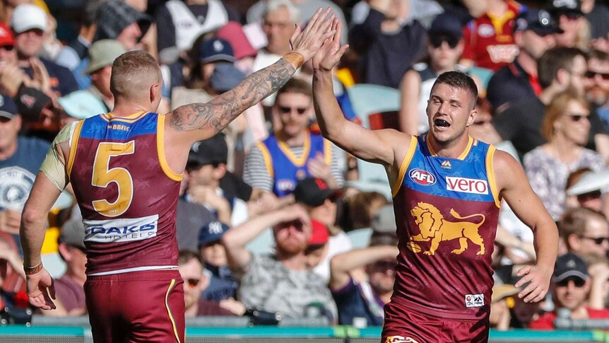 Jake Barrett and Mitch Robinson give each other a high five after a Brisbane Lions goal.