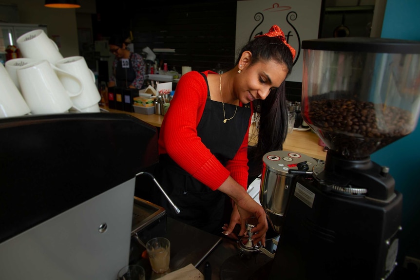A woman makes coffee at a coffee machine
