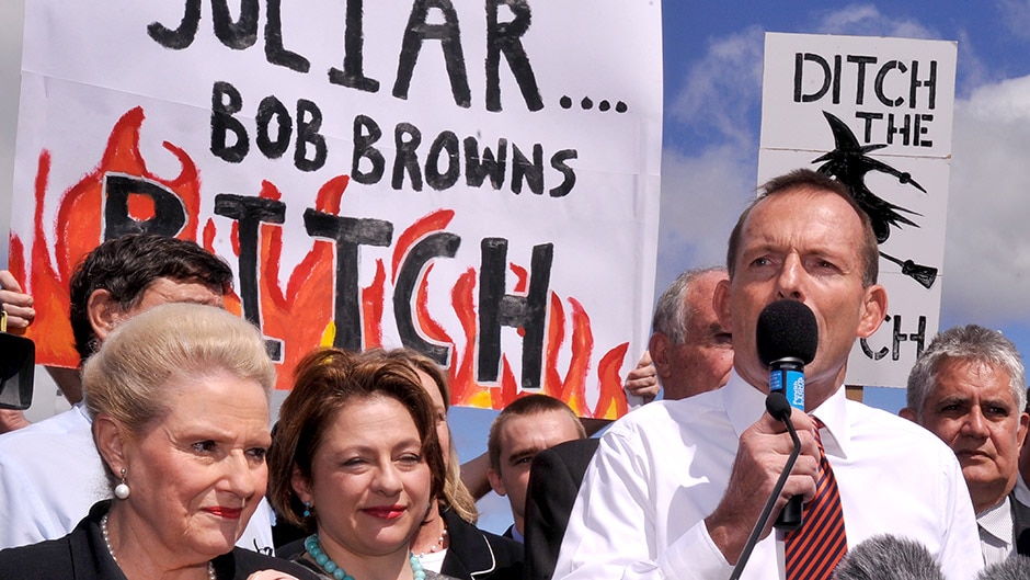 Tony Abbott addresses carbon tax protesters who are holding derogatory signs