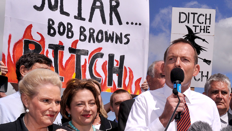 Tony Abbott addresses carbon tax protesters who are holding derogatory signs