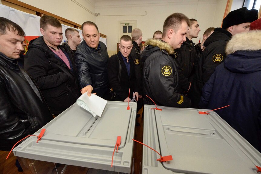Men crowd around a polling booth in vladivostok.