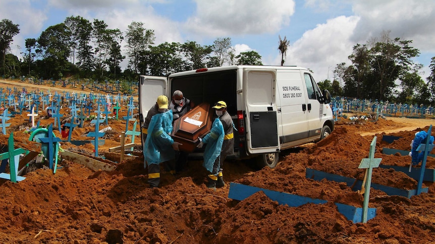 Cemetery workers unload a coffin from the back of a van amid a graveyard full of crosses  in Brazil.
