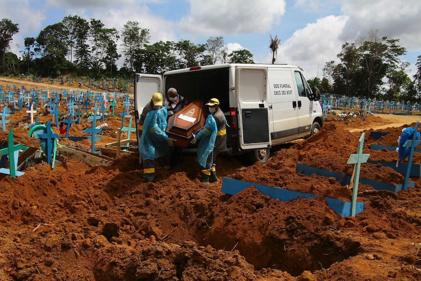 Cemetery workers unload a coffin from the back of a van amid a graveyard full of crosses  in Brazil.