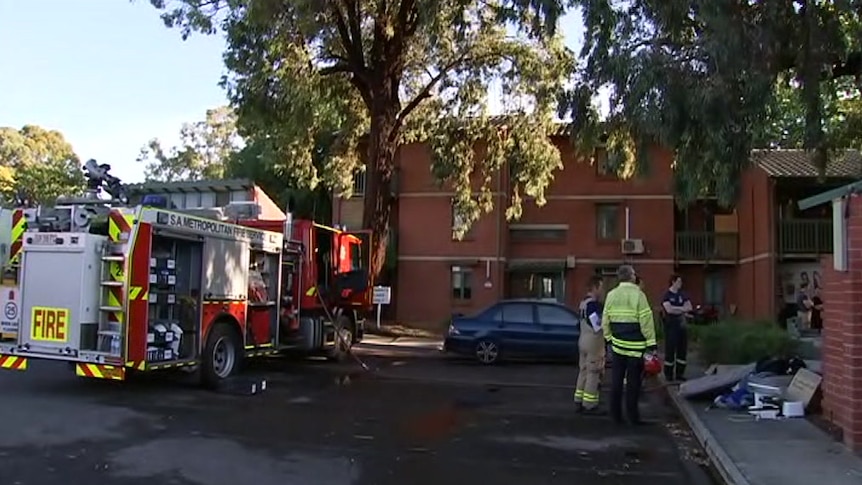 A fire truck and firefighters at a red brick unit complex