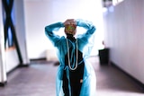 A woman in scrubs walking down a hallway with her hands on her head