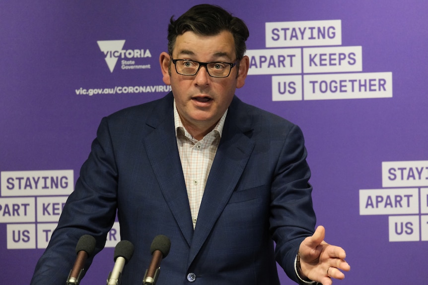 Daniel Andrews stands at a podium and speaks.