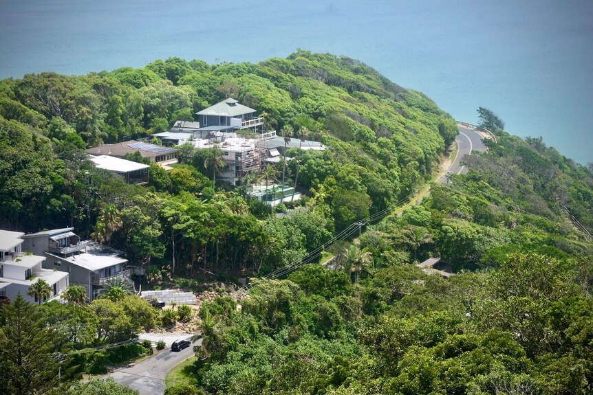An aerial photo of a hill with homes next to the sea.
