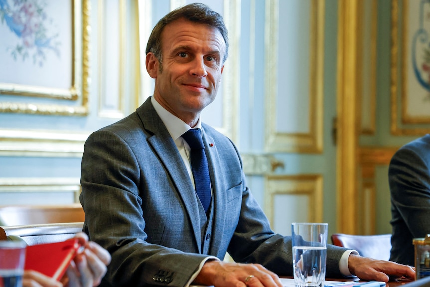 French President Emmanuel Macron sits at a table.