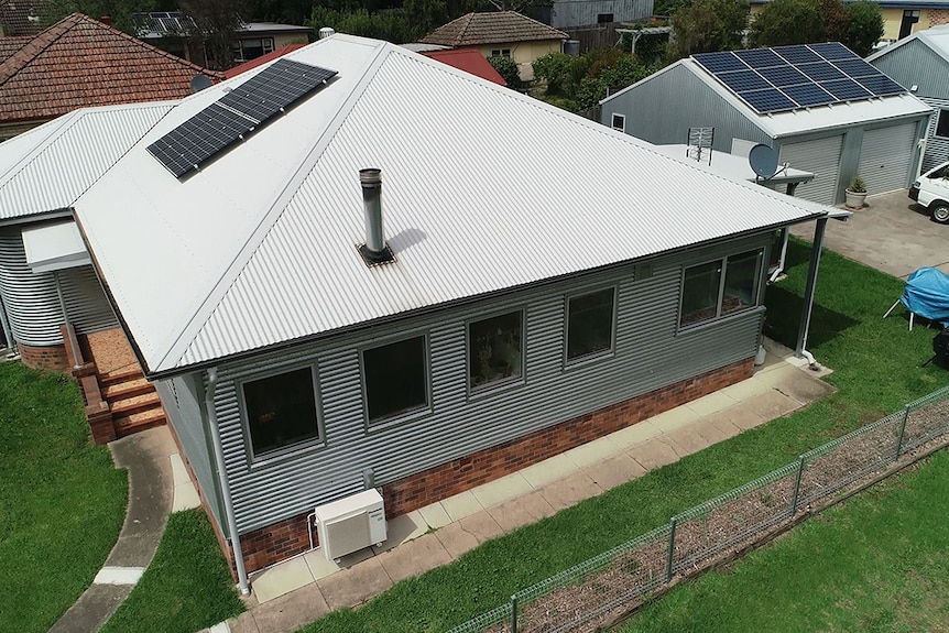 Andy Lemann's renovated fibro house with silver corrugated iron cladding and roof with solar panels, as seen from a drone.