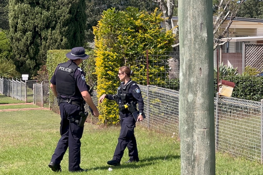 Two police stand in a front yard.