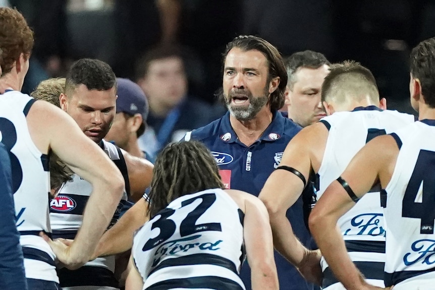 Coach Chris Scott stands in a circle of Geelong Cats players