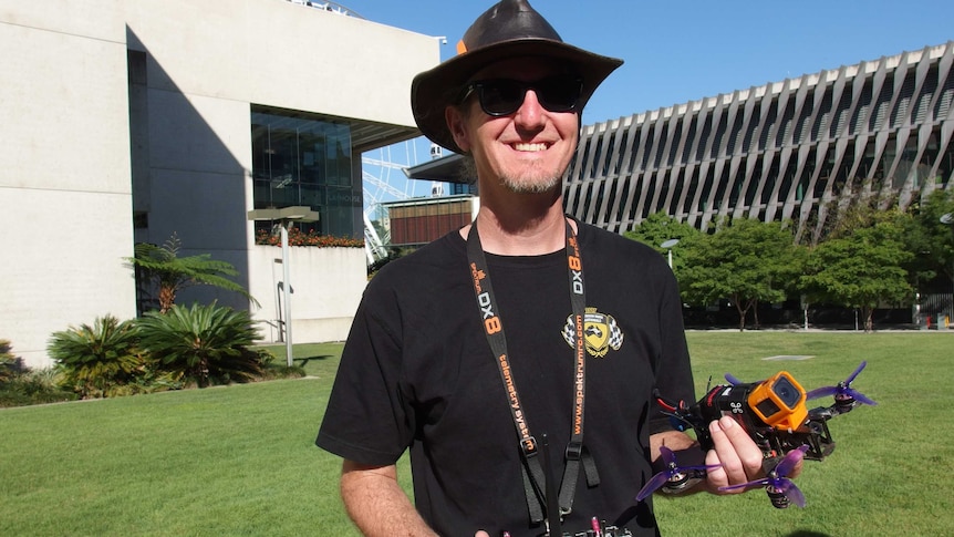 A man smiles while holding a drone and controller.
