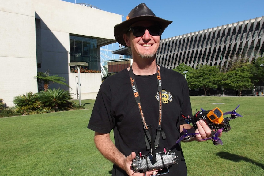 A man smiles while holding a drone and controller.