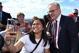 Anthony Albanese smiling as an excited voter, a young woman, takes a selfie with him.