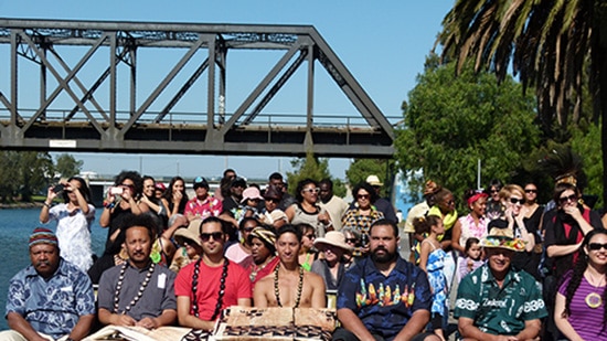 The crowd watches traditional Pacific displays on the banks of the Maribyrnong River
