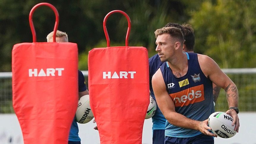 A rugby league player shapes to pass the ball during a training drill.