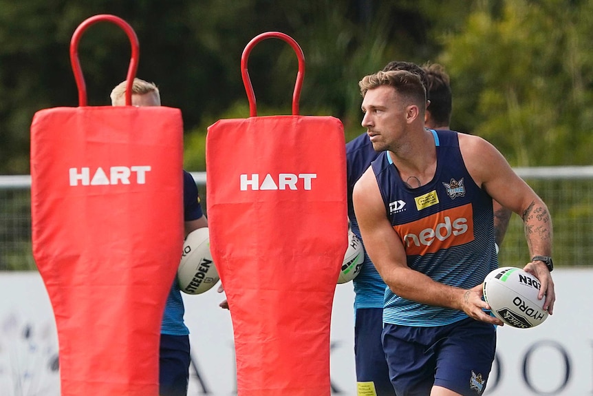 A rugby league player shapes to pass the ball during a training drill.