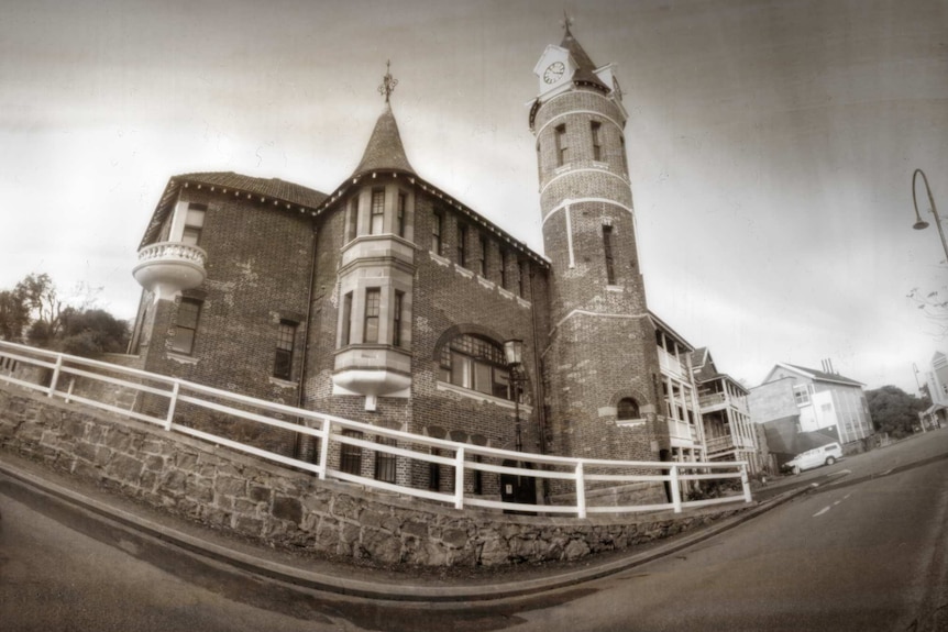 A seipa image of a road and old brick building with a clock tower.