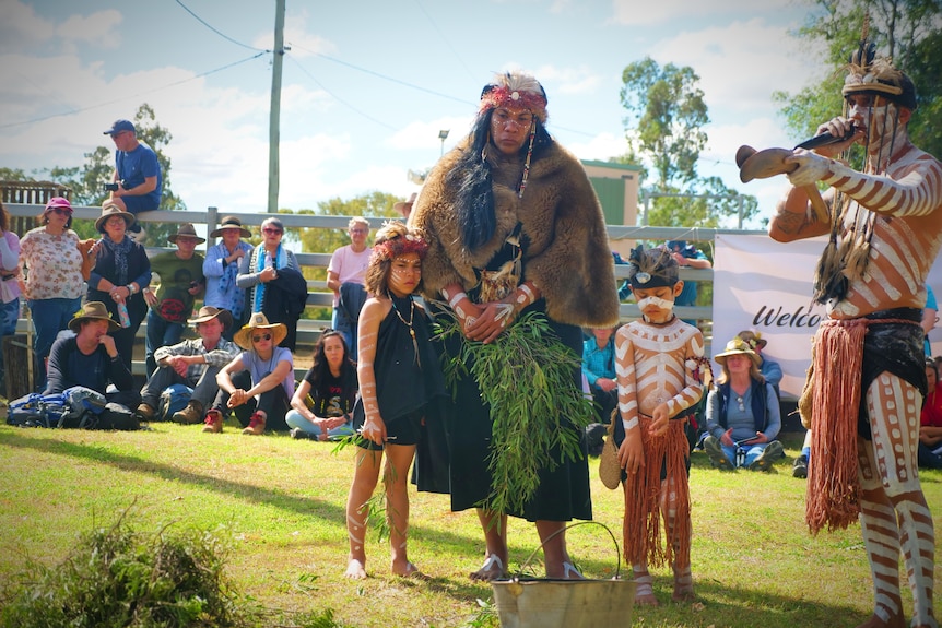 A woman in traditional dress stands with a boy and a girl.