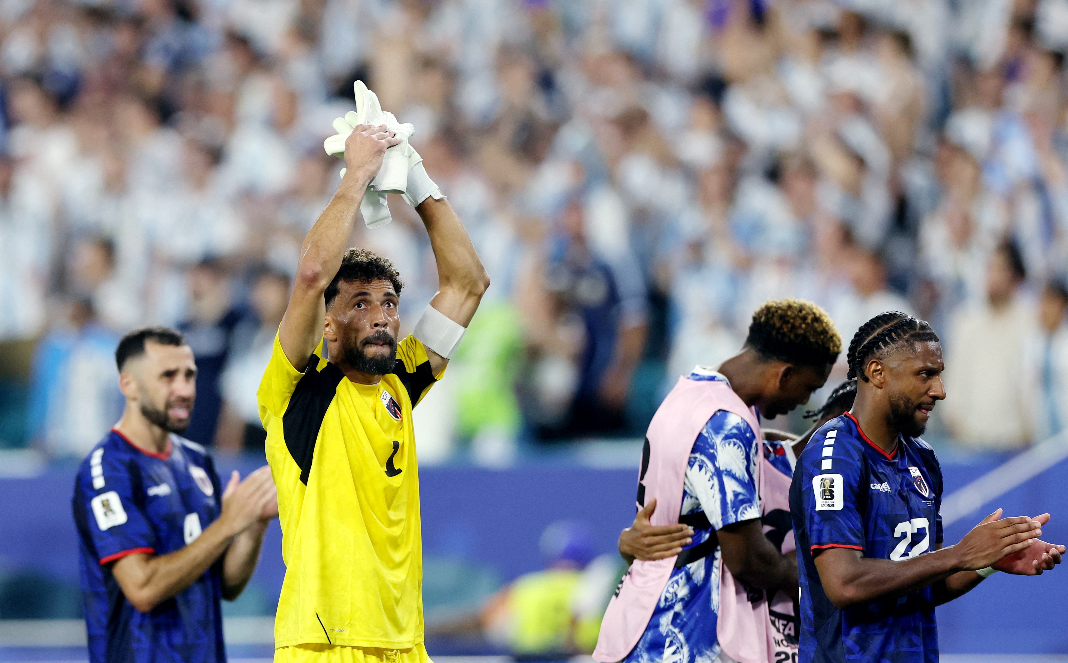 Football player with arms raised clapping hands in stadium 