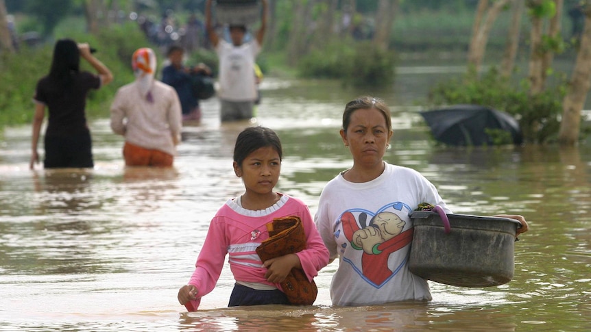 Indonesian women wade through flood in Ponorogo.