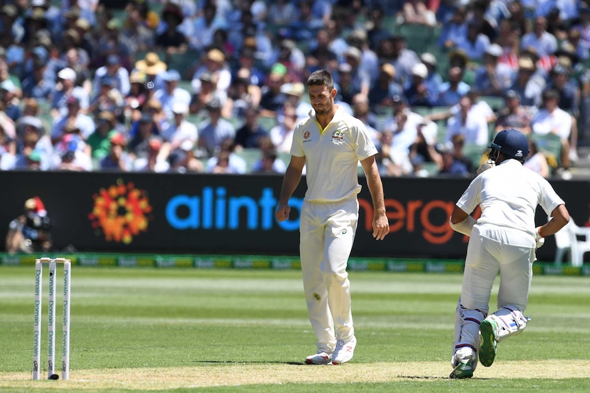 Mitch Marsh looks downwards at the pitch while walking back to his mark.